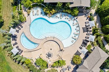 An aerial view of a well-maintained saltwater outdoor swimming pool with lounge seating and beautiful landscaping at Stonepost Crossing in Overland Park, KS.
